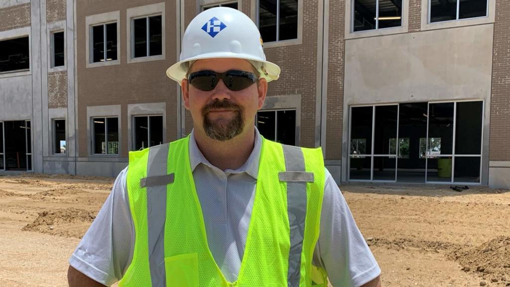 澳门足彩app's Superintendent Sonny Carter posing on a job site wearing a hard hat and safety vest.